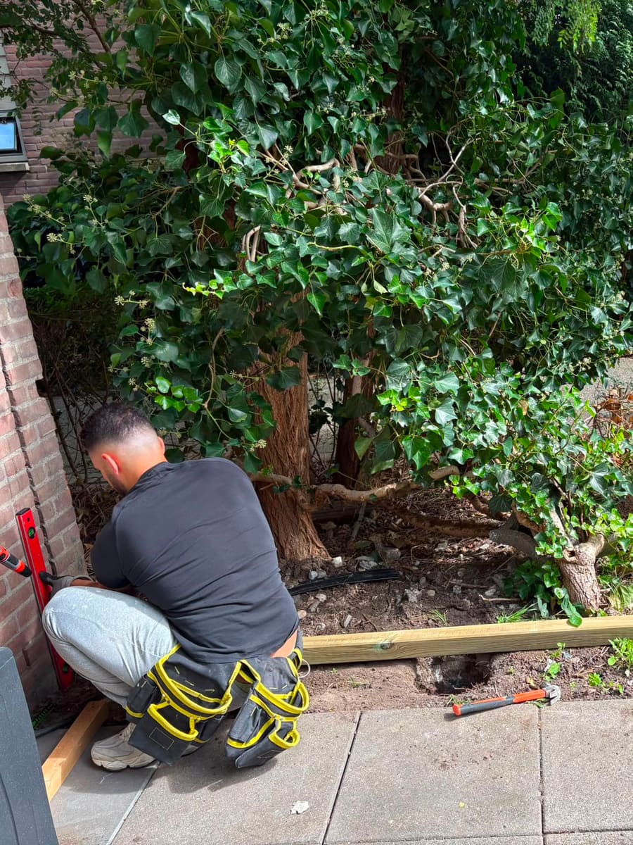 Timmerman zet met een waterpas een staander van de berging waterpas en verankert hem in de grond